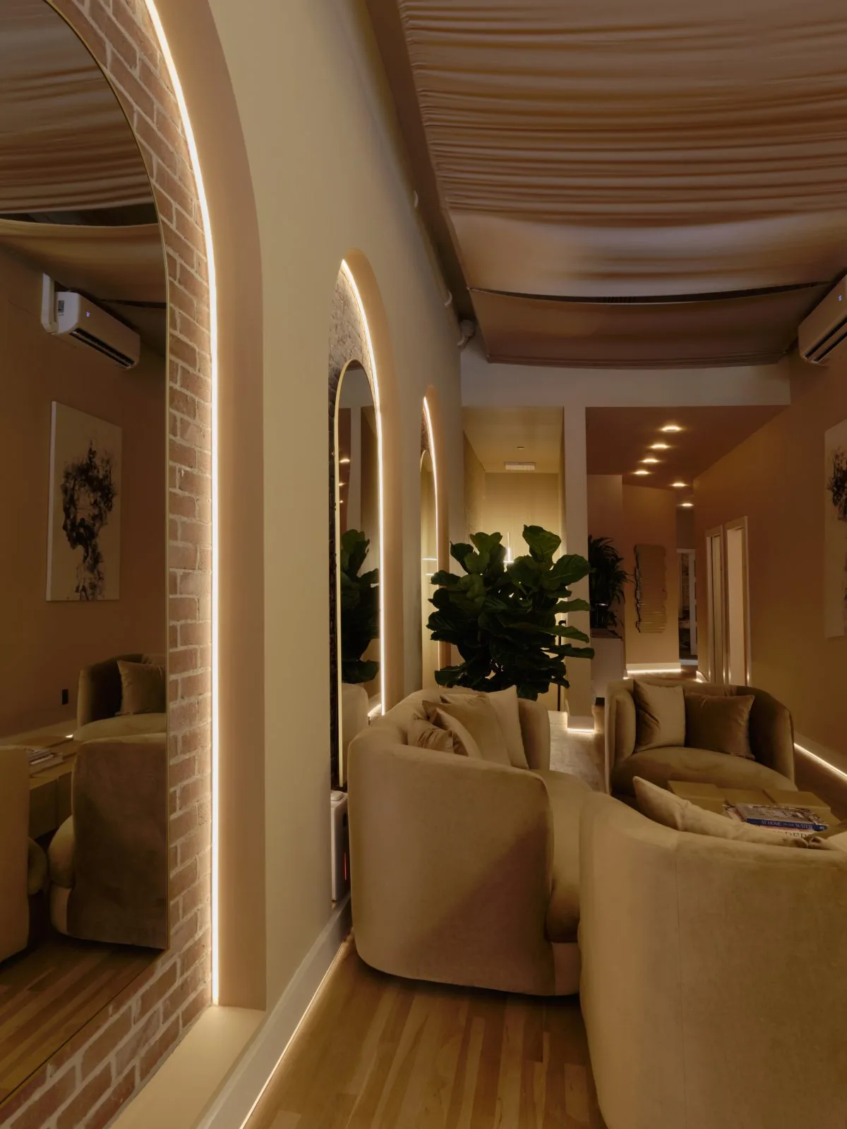 Modern consultation room at La Reservé with neon-lit mirrors, cream seating, and potted plants